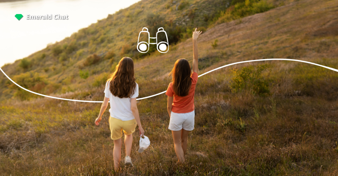 Two girls walking through a grassy field during sunset, with a doodle of binoculars overhead to show exploring what kind of friendships you want.